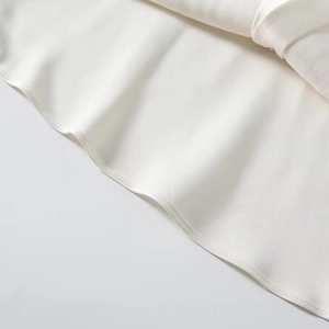 Macro detail showing smooth white satin fabric texture and precise hem stitching quality