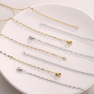 Detailed view of gold and silver stainless steel flat oval link chains on a white plate