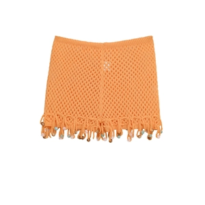 Detail of orange crochet mini skirt featuring hollow knit patterns and colorful beads