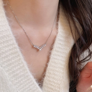 Close-up of elegant silver V-shaped pearl necklace with sparkling zircons on a model