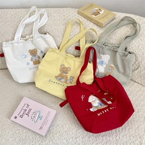 Detail of four colorful canvas tote bags with cute cartoon animal embroidery and drawstrings