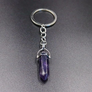 Detail of polished purple hexagonal crystal column pendant with silver metal keychain