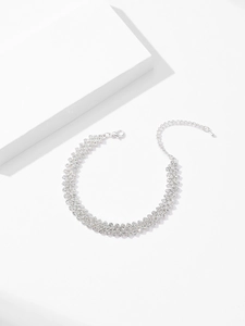 Detail of silver sparkling rhinestone necklace with lobster clasp on white stone display