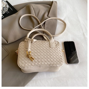 Detail of off-white woven Boston bag featuring gold hardware and a long shoulder strap
