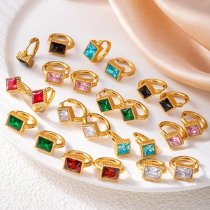 Gold star earrings with square emerald and colorful crystals displayed on white tray