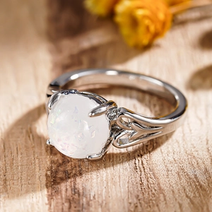 Macro shot of silver ring featuring a large round opal and hollow heart side details
