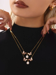 Gros plan d'un collier doré double épaisseur avec papillons roses et perles sur le mannequin