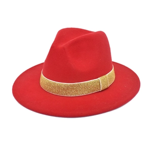 Detail of red fedora hat featuring a gold glitter decorative band on wide brim