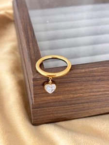 Detailed view of a gold heart pendant ring with micro-set zircon on premium silk background