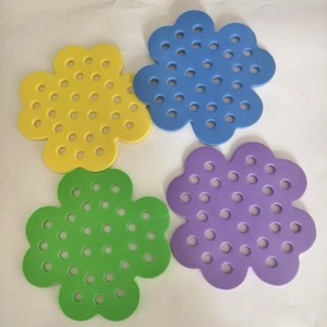Detail of four colorful flower-shaped non-slip mats with drainage holes for bathroom use