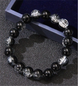 Detailed close-up of obsidian and white crystal beads on a dark blue velvet gift box