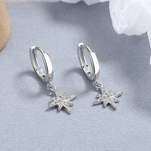 Detail view of 925 sterling silver hoop earrings with zircon-studded starburst pendants