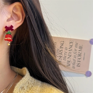 Detail of beaded Christmas tree earring with velvet bow and golden bell on model