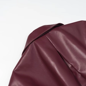 Détail de la veste en cuir bordeaux montrant la texture raffinée et les finitions
