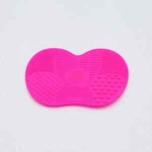 Pink silicone makeup brush cleaning mat with suction cups and various scrub textures