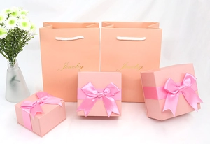 Pink jewelry gift boxes and matching bags with satin bows and golden text detail