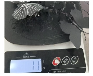 Détail d'une pince à cheveux papillon noire pesant 11g sur une balance numérique