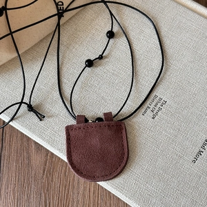 Detail of a brown faux leather U-shaped magnetic glasses holder necklace on a wooden table