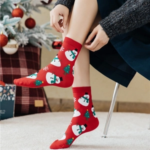 Red Christmas crew socks featuring snowman and tree patterns in a festive setting