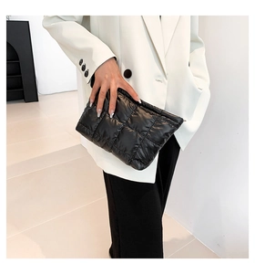 Detailaufnahme der schwarzen Puffer-Clutch mit quadratischer Steppung und Metall-Reißverschluss