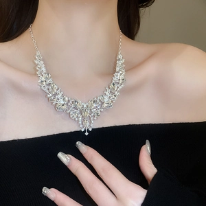 Close-up of V-shaped silver pendant necklace with sparkling diamonds on a model's neck