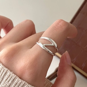 Detail of minimalist 925 silver criss-cross ring worn on finger with a knit background