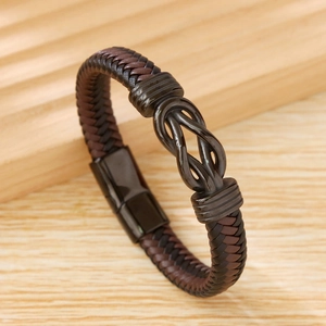 Close-up of a woven dark brown leather bracelet with a dark metal knot on wood