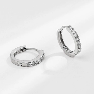 Detailed view of silver hoop earrings with shimmering zircons in classic Huggies style