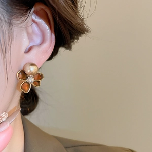 Detail view of flower earrings with gold petals and pearl center worn by a model