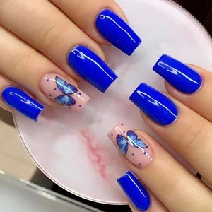 Détail de nail art papillon bleu sur faux ongles longs carrés avec finition brillante