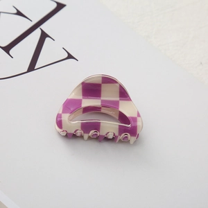 Detail of a purple and cream checkered hair claw clip showing its unique curved texture