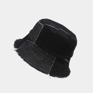 Detailed close-up of frayed edges and contrast stitching on black patchwork denim bucket hat
