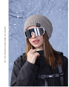 Détail d'un bonnet gris en maille gaufrée avec écusson montagne pour sports d'hiver extérieurs