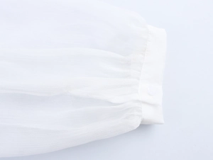 Close-up of white chiffon sleeve cuff with elegant button detail and pleated texture