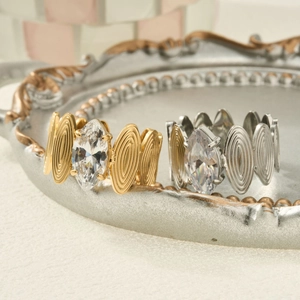 Macro detail of marquise cut stone rings with textured oval link bands on vintage tray