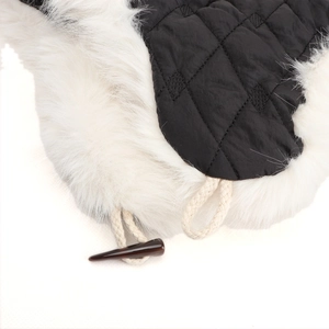Detail der Wintermütze mit schwarzem Steppmuster, Kunstfell und dekorativem Hornknopf