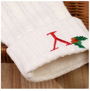 Detail of white knit Christmas stocking with red embroidered letter Y and holly leaves