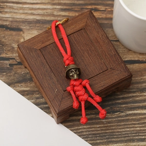 Retro skeleton skull keychain with red paracord weaving and bronze helmet on wood background