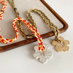 Detail of handmade floral pendants on vibrant woven ropes displayed on a wooden tray