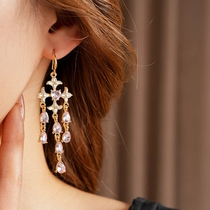 Detailed close-up of golden chandelier earrings with pink heart stones on a model