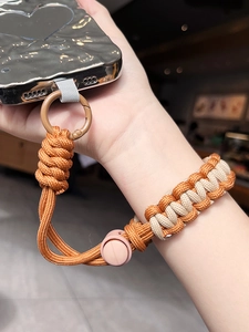 Close-up of adjustable orange and beige braided phone wrist lanyard with carabiner
