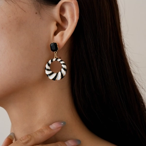 Close-up of model wearing black and white striped enamel earrings with rhinestones