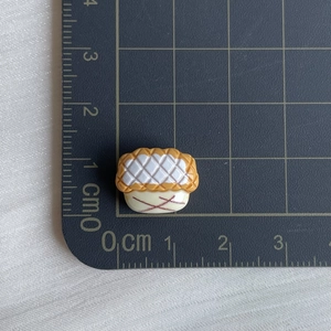 Macro shot of miniature 1.5x1cm resin pineapple bun model showing texture and scale