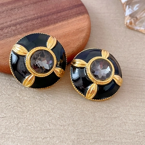 Macro shot of vintage black flower earrings with gold edges and smokey grey gemstones
