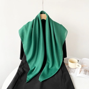 Detail of lightweight green cotton linen scarf draped softly against a minimal background