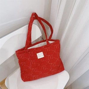 Close-up of red quilted tote bag with white rabbit outlines and square fabric label
