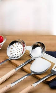 Three-piece stainless steel kitchenware set with heat-resistant wooden handles on a board