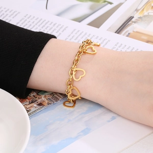 Close-up of a stylish 18K gold-plated heart charm bracelet worn on a woman's wrist