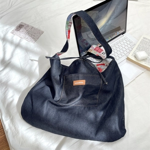 Detail of blue denim tote bag with vintage floral lining and leather logo patch