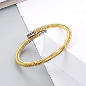 Detailed shot of gold-tone cable spring bracelet with polished silver metal end caps